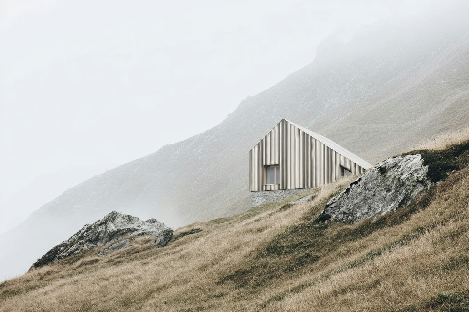 Small gabled cabin with vertical ribbed cladding on a misty hillside
